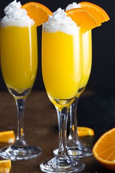 two glasses filled with orange juice and topped with whipped cream