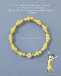 a bracelet with yellow and white beads is shown next to a small figurine