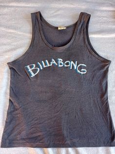 "Vintage dark grey tank top with 'Billabong' across the front and an illustration of waves on the back.  50/50% Cotton/Polyester Measurements lying flat: Width (across the chest): 17 inches Length: 22.5 inches Tag: Mens 14  This item is in good vintage condition! All items are stored in a smoke-free environment   Lowbrow Vintage is based in Tucson, Arizona, and is an entirely independent and family run business. At Lowbrow Vintage, we focus on curating a unique and funky aesthetic, while still leaving room for comfort and charm. We hope that these wonderful pieces are appreciated once again in the cycle of vintage love. We care deeply about vintage fashion and do our best describe and photograph each item with care and detail. Our pieces are well loved ready and waiting for a new life in t Vintage Tank Top For Summer Beach, 90s Cotton Tank Top For Streetwear, Vintage Tank Top For Streetwear, Vintage Summer Tank T-shirt, Vintage Billabong, 90s Crew Neck Cotton Tank Top, Funky Aesthetic, 80s And 90s Fashion, Grey Tank Top