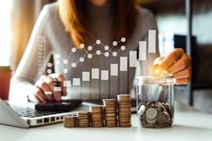 business woman stacking coins in front of her laptop and stacks of coins on the table