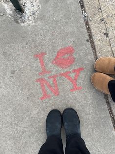 two people standing next to each other near a sidewalk with the words i love new york painted on it