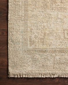 an area rug with fringes on top of wooden flooring and a wood table