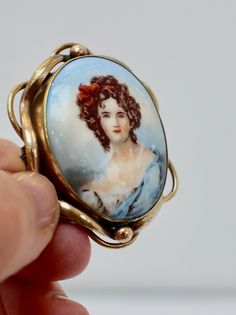 Pinchbeck Painted Cameo Brooch Details ~  Super antique brooch with hand painted porcelain portrait, depicting a lovelyl 19th century lady in blue, her hair in ringlets tied up in a red ribbon.  It has a rather grand pinchbeck setting which is typical of the traditional Victorian brooch, and has a bar and C clasp fastening. c 1850s. It would make a super gift, for a birthday or just a treat! Measures ~  5cm X 4cm  ( approx 2" x 1.5" in inches) Condition ~  Good vintage condition. Thank you for your interest Please read the shop policies before purchasing as they contain important information about payment and shipping to help you Victorian Style Enamel Pin Gift, Faux Pearl Jewelry, Victorian Brooch, Vintage Givenchy, Glitter Crafts, Faux Pearl Earrings, Super Gifts, Antique Brooches, Cameo Brooch