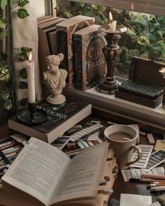 an open book sitting on top of a table next to a candle and some books