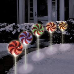 lighted candy lollipops in front of a house on a snowy day at night