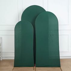 two green chairs sitting next to each other on top of a hard wood floor in front of a white wall