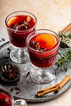 two glasses filled with mulled wine and cinnamon sticks