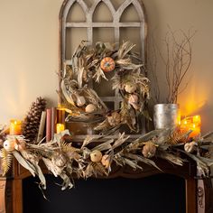 a fireplace mantel decorated with dried leaves and pumpkins, candles and pine cones