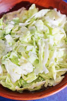 a wooden bowl filled with lettuce on top of a blue table