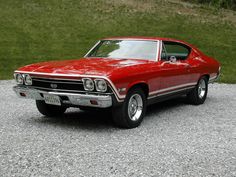 a red car parked on top of a gravel road