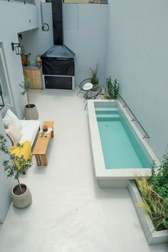 an indoor swimming pool in the middle of a patio with furniture and potted plants