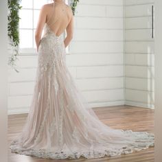 a woman in a wedding dress standing on a wooden floor with her back to the camera