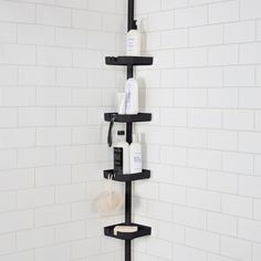 there is a black shelf in the shower that has several bottles and soaps on it