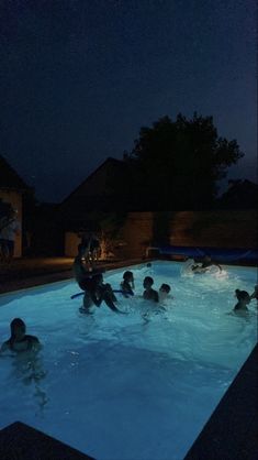 people are swimming in the pool at night