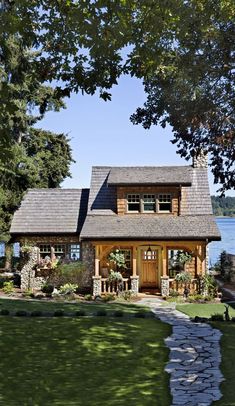 a small house sitting on top of a lush green field next to a body of water