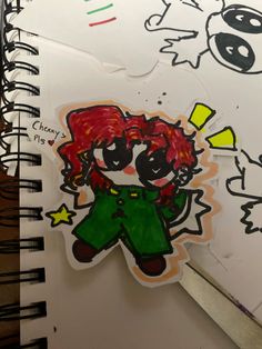 a drawing of a girl with red hair and green pants is on top of a spiral notebook