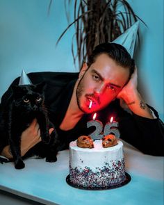 a man laying on top of a table next to a cake with candles in it