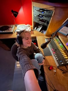 a woman wearing headphones sitting in front of a microphone and sound equipment on a table