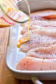 raw fish being poured into a pan with seasoning on top and in the bottom