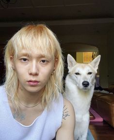 a woman with blonde hair sitting next to a white dog