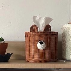 a wicker basket with a bear face on it and two spools of yarn next to it