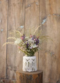 a white lace vase filled with flowers on top of a wooden stump