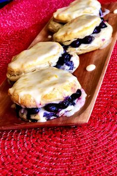 three blueberry scones are on a wooden plate