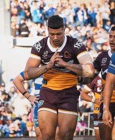 two rugby players standing next to each other in front of a crowd looking at their cell phones