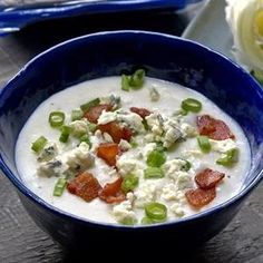 a blue bowl filled with soup on top of a wooden table