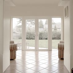 an empty room with two chairs and sliding glass doors that lead to the back yard