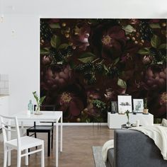 a living room filled with furniture next to a wall covered in floral art work on the walls