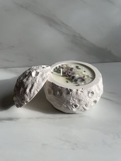 a white candle sitting on top of a marble table next to an object that looks like a rock