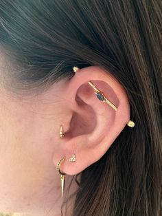 a woman's ear with three different piercings on the top and bottom of it