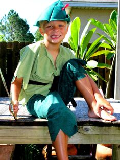 a young boy sitting on top of a wooden bench