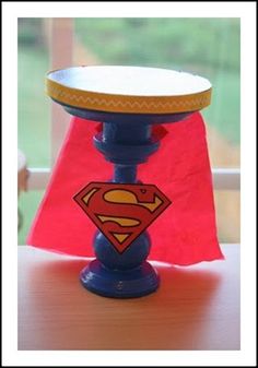 a blue candle holder with a superman symbol on it and a red flag in the background