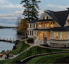 a large house sitting on top of a lush green field next to a body of water