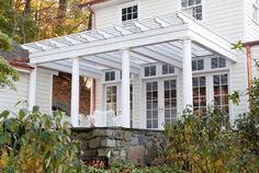 a white house with an awning over it's porch and covered patio area