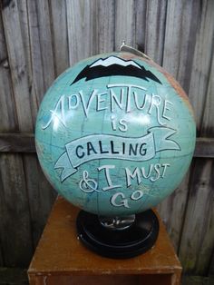 a globe with writing on it that says adventure is calling and i must be 9 o'clock