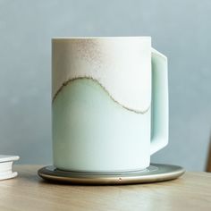 a white and green coffee cup sitting on top of a wooden table next to a stack of books