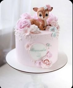 a pink cake decorated with flowers and a baby deer