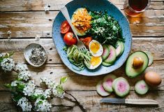 a blue bowl filled with lots of different types of food on top of a wooden table