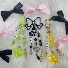 several different types of key chains on a white furnishing with black and pink bows