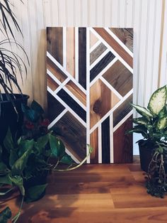 two potted plants sitting on top of a wooden table next to a large painting