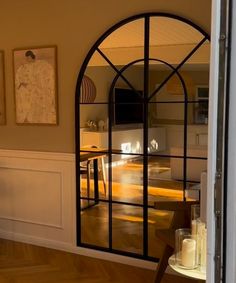 an arched glass door with candles in front of it on a hard wood flooring area