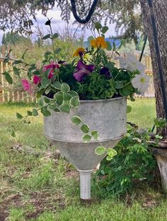 a planter filled with lots of flowers next to a tree