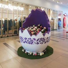 a large egg with flowers in the middle of it on display at a shopping mall