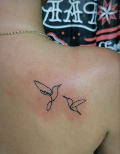 the back of a woman's shoulder with two birds on it