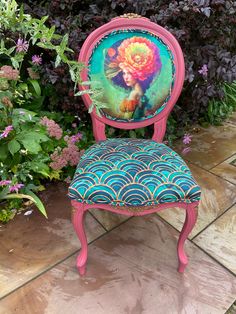 a pink chair with an image of a mermaid on it's back sitting in front of some flowers