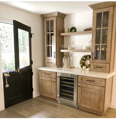 a kitchen with wooden cabinets and white counter tops next to a black door that leads to a patio