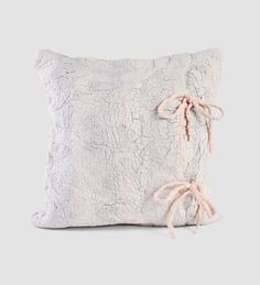 a white pillow with pink bows on the front and back of it, against a gray background